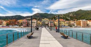 a pier with benches and buildings next to the water at Oasi Relax Alassio Riviera in Alassio