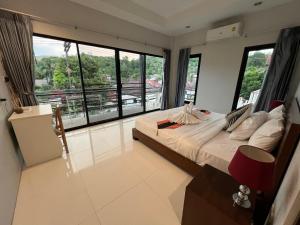 a bedroom with a bed and large windows at Nern khao Guesthouse in Kamala Beach