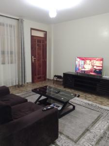 a living room with a couch and a table and a tv at Raah residence in Nairobi