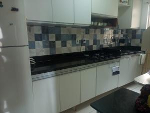 a kitchen with white cabinets and a black counter top at Apto-VOG-Ilheus in Ilhéus