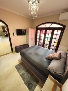 a bedroom with a large bed and a chandelier at Casa com Piscina em Cabeçudas , 80 metros da Praia in Itajaí
