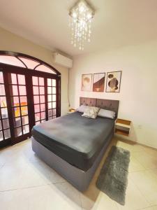 a bedroom with a large bed and a chandelier at Casa com Piscina em Cabeçudas , 80 metros da Praia in Itajaí
