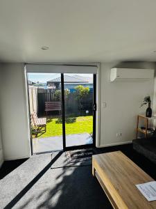 a living room with a sliding glass door to a patio at Tiny Home in Mosgiel in Mosgiel