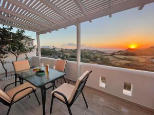 a table and chairs on a balcony with a sunset at SUMMER House 2 in Vívlos