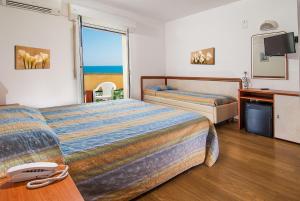 a hotel room with two beds and a television at Hotel Alba Serena in Misano Adriatico