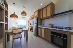 une cuisine avec des placards en bois et une table ainsi qu'une salle à manger dans l'établissement Ocean Front Apartment in Buzios Praia Caravelas, à Búzios 19 autres photos