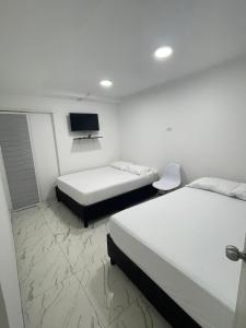 ein Hotelzimmer mit zwei Betten und einem Fernseher in der Unterkunft Hotel Lago Cartagena in Estación El Salto
