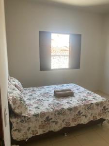 a bedroom with a bed with a blanket and a window at Casa Bela Vista II in São Roque de Minas