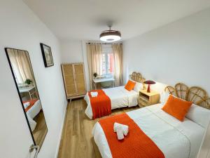 a bedroom with two beds with orange and white at El Rinconín - Tu Casa En Gijón in Gijón