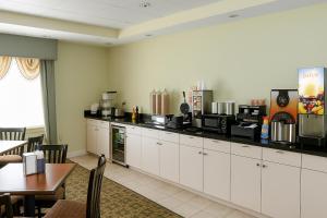 a kitchen with white cabinets and a table and a counter at Ambassador Inn & Suites Tuscaloosa University I-20 in Tuscaloosa