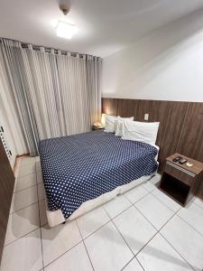 a bedroom with a bed with a blue and white comforter at Nobile Suites, Flats Rocha in Brasília