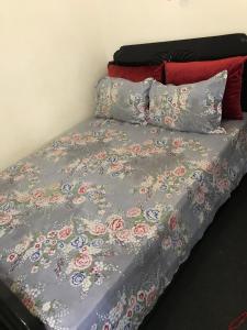 a bed with a gray comforter with flowers on it at paradis in Aït Bou Setta