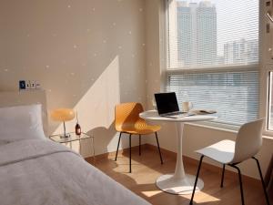 a bedroom with a bed and a desk with a laptop at Cozy Seomyeon House in Busan