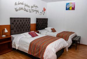Un dormitorio con dos camas y un cartel en la pared. en Magic Cusco, en Cusco 6 fotos más