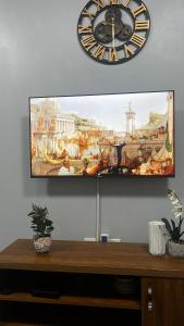 a clock on the wall above a tv on a wall at Havillah Suites Kololo in Kampala