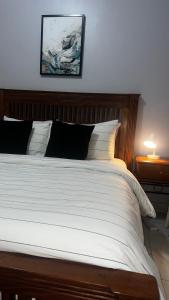 a bedroom with a white bed with a wooden headboard at Havillah Suites Kololo in Kampala