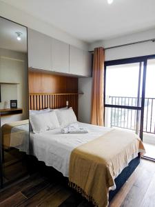 サンパウロにあるLoft 12º City Viewの大きなベッドと大きな窓のある寝室