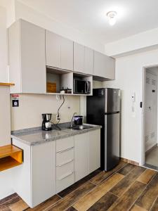 サンパウロにあるLoft 12º City Viewの白いキャビネットと黒い冷蔵庫のあるキッチン