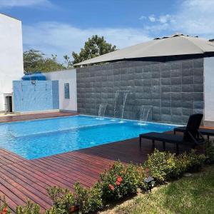 a swimming pool with an umbrella and a chair at Zorritos beach house in Zorritos