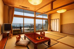 a living room with a table and a large window at Ooedo Onsen Monogatari Premium Hotel Fugetsu in Beppu +61 photos