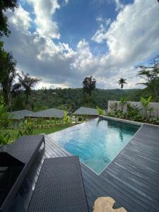 a large swimming pool with a wooden deck next to at Micaela Bali Ubud Villas in Tegalalang