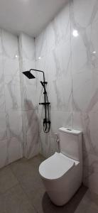 a white bathroom with a toilet in a room at Emerald Villa in Prampuan