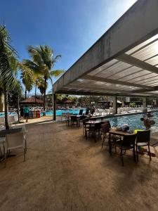 a patio with tables and chairs next to a pool at Hotel suits Le jardin in Caldas Novas