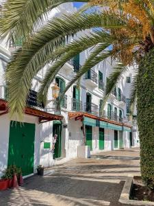 Una palmera frente a un edificio con puertas verdes. en Central - Fast Internet - First Choice, en Tetuán