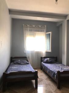 two beds in a room with a window at Appartement en bord de mer 3 chambres in Aguemoun Taïda