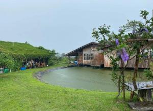 a house with a pond in the middle of a yard at Uncle Ong Home's Khaokho บ้านพักลุงโอ่งโฮม เขาค้อ in Khao Kho