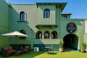 a green building with a table and chairs and an umbrella at De Blasis Budget Rooms in Santiago +199 photos