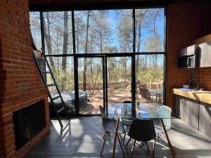 a dining room with a glass table and a fireplace at Cozy cabin in the woods with a wooden tub in Huasca de Ocampo