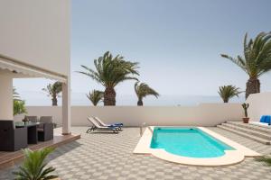 a swimming pool in the middle of a patio with palm trees at Villas Salinas in Costa Teguise