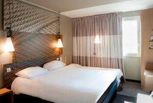 ein Hotelzimmer mit 2 Betten und einem Fenster in der Unterkunft ibis Paris Saint-Denis Stade Sud in Saint-Denis