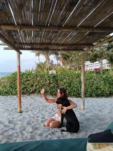 eine Frau sitzt auf dem Sand am Strand in der Unterkunft Villa Naylamp loft en las pocitas in Máncora