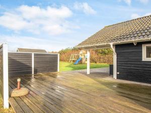 a wooden deck with a building and a playground at 8 person holiday home in Harboøre-By Traum in Harboør