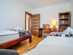 a bedroom with two beds and a desk with a desk at Vysoké Tatry - ISC RESORT in Mlynica