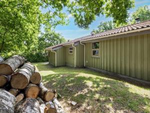 a house with a pile of logs in front of it at 6 person holiday home in Hadsund-By Traum in Øster Hurup
