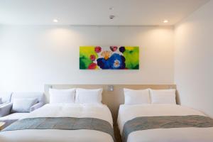 two beds in a room with a painting on the wall at Beppu Daiiti Hotel in Beppu