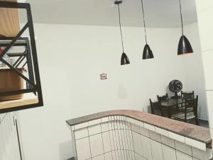 a kitchen with three pendant lights hanging over a counter at kit net Vovó nice garagem gratis in Aparecida