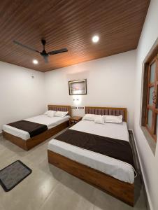 a bedroom with two beds and a ceiling fan at Mangrove Forest Camp Eco Stay Sundarbans, India in Jāmb
