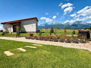 a house with a garden and mountains in the background at Vysoké Tatry - ISC RESORT in Mlynica