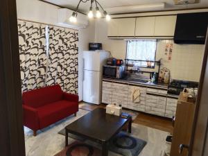 a living room with a red couch and a kitchen at ELM On The Beach in Kitaibaraki