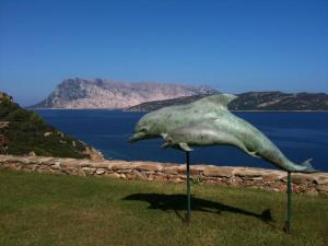 una statua di due delfini esposti vicino all'acqua di Villaggio Est a Capo Coda Cavallo San Teodoro a San Teodoro