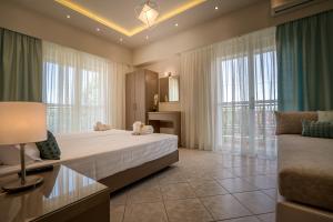 a bedroom with a bed and a couch and windows at Alba Boutique Apartments in Laganas