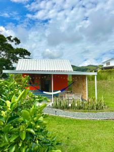 a house with a tin roof on a green field at Alojamiento Rural San José in Cartago