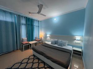 Un dormitorio con una cama y una pared azul. en LA SIESTA INDIA MCLEODGANJ, en McLeod Ganj