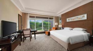 a bedroom with a bed and a desk and a television at New Century Grand Hotel Xuzhou in Xuzhou