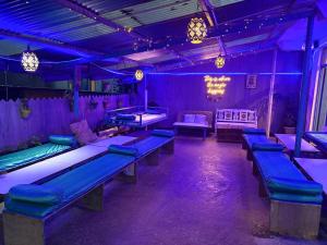 a room with purple lights and tables and benches at LA SIESTA INDIA MCLEODGANJ in McLeod Ganj