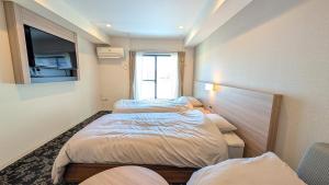 Dos camas en una habitación pequeña con ventana. en M-1 Tokyo Nishirokugo 203, en Tokio